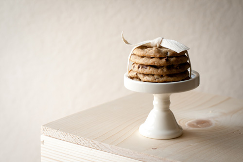 Four chocolate chip cookies stacked on ceramic stand and tied with white ribbon